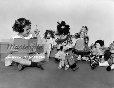 1930s LITTLE GIRL POINTING A FINGER READING BOOK TO A ROW OF DOLLS TOYS STUFFED ANIMALS