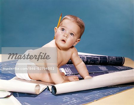 1960s BABY ARCHITECT SITTING AMONG BLUEPRINTS