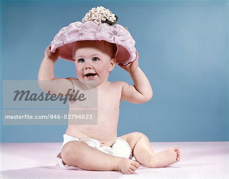 1960s SMILING BABY GIRL WEARING DIAPER AND LARGE PINK HAT