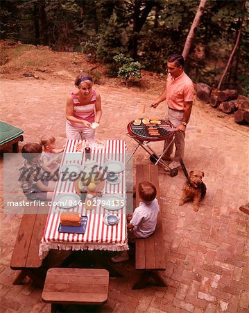 ANNÉES 1970 FAMILY MAN FILS FILLE CHIEN BACKYARD PIQUE-NIQUE BARBECUE HOT DOG HAMBURGER GRILL TABLE ARBRES