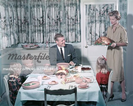 1950s HAPPY FAMILY 5 DINING ROOM TABLE MOM BRING TURKEY ON PLATTER DAD KIDS SIT INTERIOR CURTAINS MEAL BOY GIRL