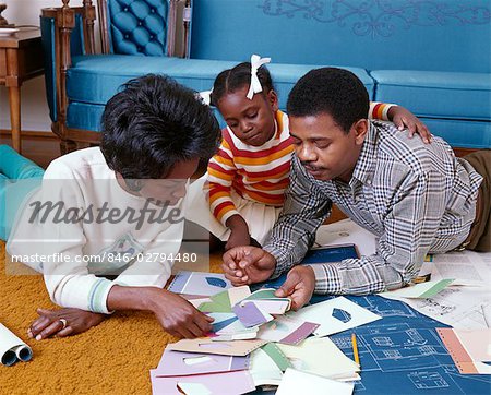 1960s AFRICAN AMERICAN FAMILY OF 3 MOM DAD DAUGHTER TOGETHER LOOK AT PAINT CHIPS BLUEPRINTS COLOR SAMPLES NEW HOME
