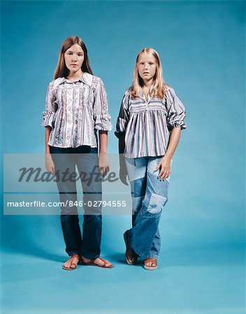 1970s PORTRAIT TWO TEEN GIRLS STANDING FULL LENGTH WEARING DENIM BLUE JEANS PEASANT BLOUSES RETRO SANDALS FASHION