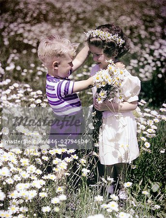 ANNÉES 50 ANNÉES 1940 GARÇON FILLE EXTÉRIEURE CHAMP DE MARGUERITES CUEILLETTE FLEURS