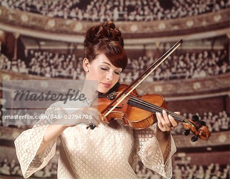 1960s WOMAN VIOLINIST PLAYING VIOLIN WEAR WHITE LACE DRESS AUDIENCE CONCERT HALL VISIBLE BACKGROUND WOMEN