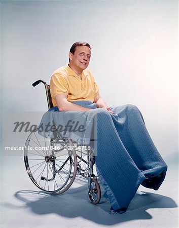 1960s SMILING MAN SITTING IN WHEELCHAIR BLANKET WRAPPED AROUND LEGS