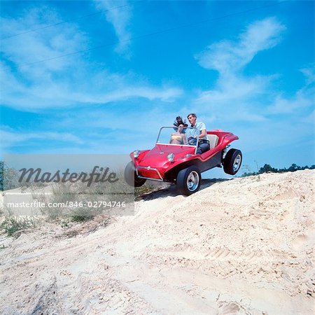 1960s 1970s TEENAGE COUPLE MAN WOMAN RIDING IN DUNE BUGGY ON BEACH
