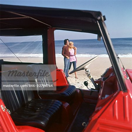 COUPLE ON BEACH STANDING OUTSIDE VEHICLE