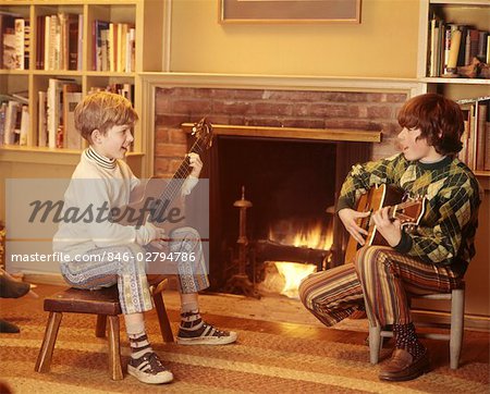 1970 1970s 2 BOYS FRONT FIREPLACE PLAY PLAYING STRUMMING GUITARS CHILDREN BOY CHILD MUSIC LIVING ROOM STOOLS