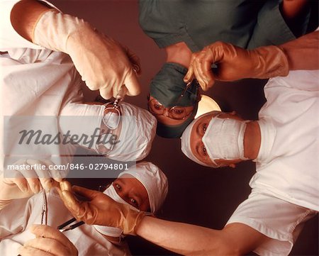 1970s 4 PERSON SURGICAL TEAM FROM BELOW PATIENT POINT OF VIEW DOCTOR NURSE SURGEON DOCTORS SURGERY OPERATION