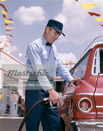 1950s 1960s SERVICE STATION ATTENDANT WITH GASOLINE PUMP HOSE FILLING GAS TANK OF AUTOMOBILE
