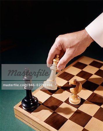 1960s MANS MALE HAND HOLDING CHESS PIECE MOVE MOVING CHECKMATE CHECK MATE STRATEGY GAME WIN