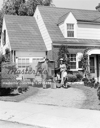 1950s FAMILY MOTHER FATHER SON IN FRONT OF SUBURBAN HOUSE LOADING CAR TRUNK WITH LUGGAGE SUITCASE GOLF BAG TRIP VACATION