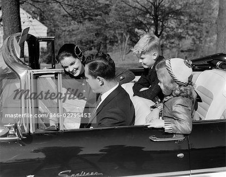 1950s FAMILY FATHER MOTHER DAUGHTER SON IN CONVERTIBLE READING MAP