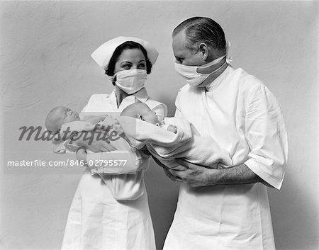 1930s 1940s MAN DOCTOR WOMAN NURSE WEARING STERILE MASKS HOLDING NEWBORN INFANT TWIN BABIES