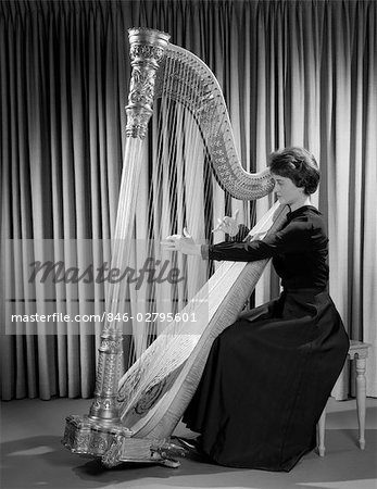 MUSICIEN FEMME DES ANNÉES 1960 EN TENUE HABILLÉE, SPECTACLE JOUÉ HARPE EN SCENE