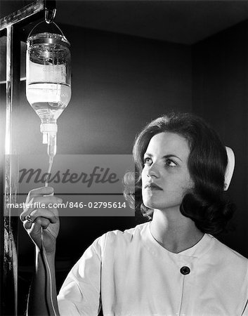 1960s WOMAN NURSE IN CAP AND UNIFORM IN EMERGENCY ROOM ADJUSTING FLOW FROM IV BOTTLE