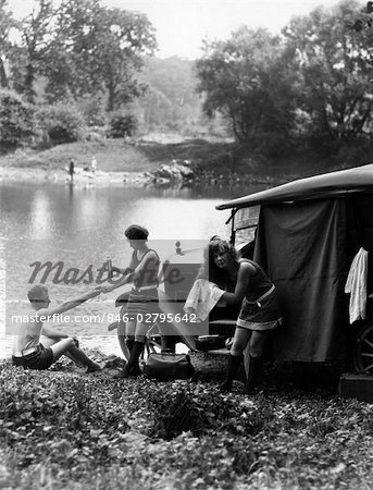 1920s GROUP OF TWO WOMEN AND ONE MAN AT LAKE WITH TOURING CAR TOWELING OFF HAIR AFTER SWIMMING