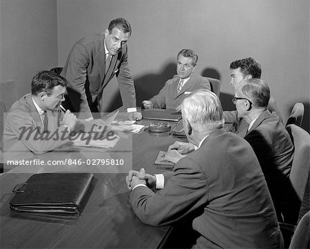 1950s SIX BUSINESSMEN EXECUTIVES AROUND A CONFERENCE TABLE TALKING