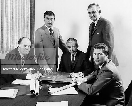 1970s FIVE MEN EXECUTIVES AROUND BUSINESS CONFERENCE TABLE LOOKING AT CAMERA