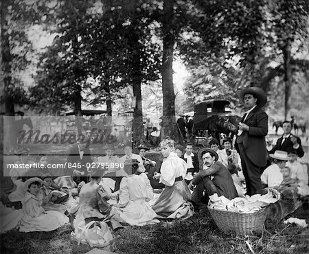 1890s 1900s TURN OF THE CENTURY GROUP HAVING PICNIC IN WOODS WITH HORSES & WAGONS IN BACKGROUND