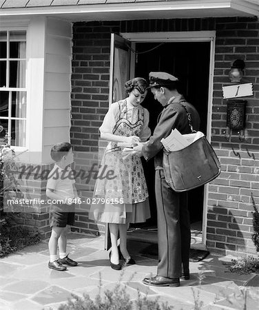 1950ER JAHRE SUBURBAN MOM AT HOME HAUSTÜR MIT SOHN GERADE EMPFANG-PAKET VON MAILMAN