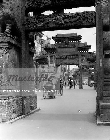 1920s 1930s RICKSHAW ON STREET IN CANTON CHINA UNDER ORNATE CARVED ARCHES ANCIENT PAI-LOUS CHINESE ARCHITECTURE