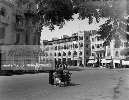 ANNÉES 1930 ANNÉES 1920 RUE SCÈNE ARCHITECTURE EN ARABE STYLE VENDER POUSSANT LE CHARIOT BANLIEUE DE CAIRO HELIOPOLIS EGYPTE