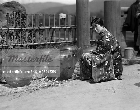 ANNÉES 1930 SANS SOURIRE JAPONAIS KIMONO FEMME EN SE METTANT À GENOUX DE MARCHÉ GROUPE OR GRAND RUE DES BACS À POISSONS POISSONS ROUGES À KOBE AU JAPON