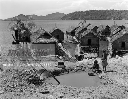 1920s 1930s WATER HOLE TWO NATIVE CHILDREN VILLAGE OF HANUABADO STRAW GRASS HOUSES HUTS ON STILTS NEW GUINEA