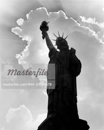 SILHOUETTE OF STATUE OF LIBERTY WITH CLOUDS BEHIND HER