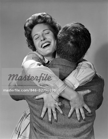 ANNÉES 1950 COUPLE HOMME ET FEMME HEUREUSE EMBRASSENT ÉTREINDRE