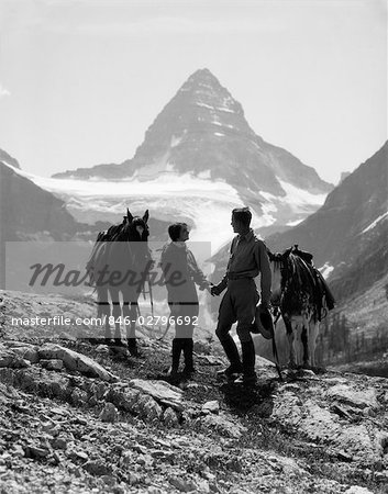 1930s COUPLE MAN WOMAN HOLDING HANDS STANDING WITH HORSES IN MOUNTAINS WESTERN MT. ASSINIBOINE CANADA