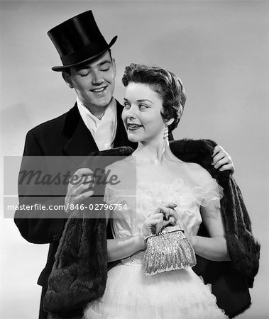 Années 1950 Couple Tenue De Ville Homme Femme Aidant Portant