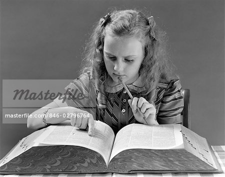 1940s YOUNG GIRL LOOKING IN DICTIONARY HOLDING PENCIL TO CHIN