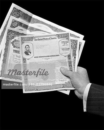 1940s MANS HAND HOLDING 4 STOCKS BONDS CERTIFICATES DOCUMENTS VALUE 1000 DOLLARS FINANCE STOCK SAVINGS BOND BANKING WEALTH