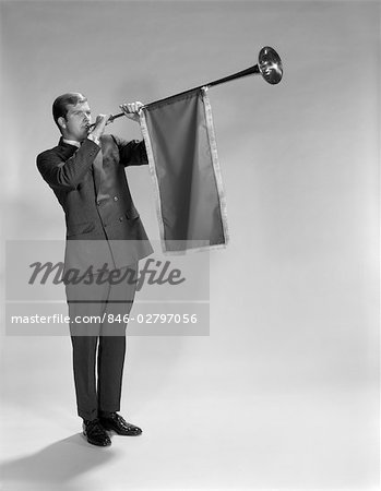 1960s YOUNG MAN STANDING BLOWING HERALD'S HORN
