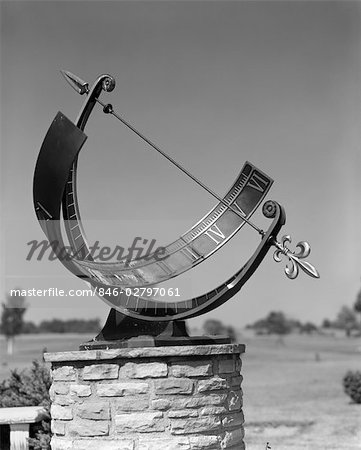 SUNDIAL STONE PEDESTAL METAL BAR ROMAN NUMERALS SHADOW CREATED BY METAL BOW & ARROW SUN SOLAR TIME DAY OUTDOORS HOURS MINUTES