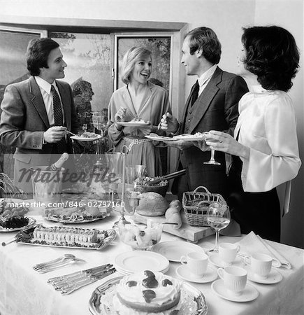 ANNÉES 1980 PAIRE DE COUPLES CHAT SUR LES BOISSONS & FOOD AT BUFFET TABLE