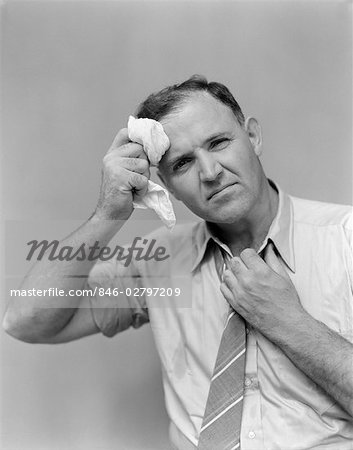 1940s BUSINESS MAN IN SHIRT AND TIE HOLDING HANDKERCHIEF WIPING FOREHEAD