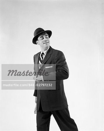 1950s MAN IN BUSINESS SUIT HOLDING OUT FOREARM AS IF TO TAKE A PARTNER'S ARM