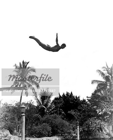 1930s MAN POISED MIDAIR ARMS OUT JUMPING FROM DIVING BOARD INTO POOL