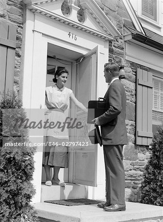 1950s SALESMAN AT DOOR TALKING TO HOUSEWIFE