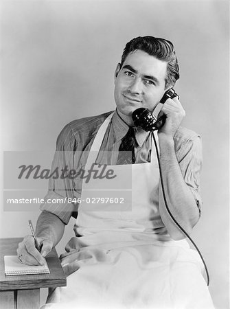 ANNÉES 1930 1940 HOMME PORTANT TABLIER TALKING TÉLÉPHONE ÉCRIT VERS LE BAS DE L'ORDRE