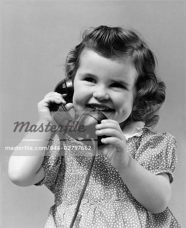 1930s LITTLE GIRL SMILING SHOWING DIMPLES TALKING ON TELEPHONE