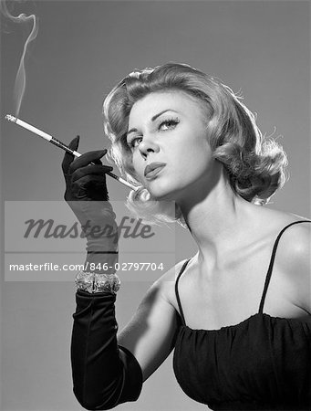 ANNÉES 1960 FEMME SENSUELLE SEXY EN NOIR ROBE GANTS NOIR BRACELET FUMER CIGARETTE EN LONG FUME-CIGARETTE