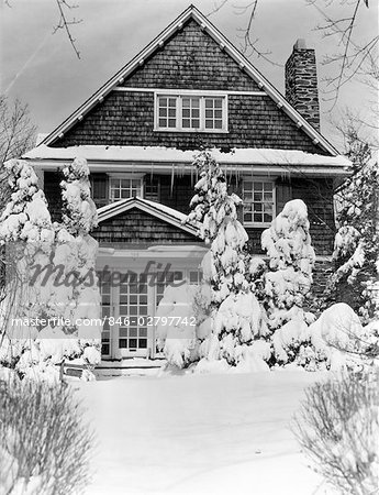 1940s THREE STORY HOUSE WITH PINE TREES AND SHRUBS COVERED WITH SNOW