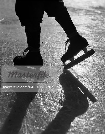1930s FIGURE SHOWN FROM KNEES DOWN WEARING ICE SKATES SKATING IN ICE SUN GLARE