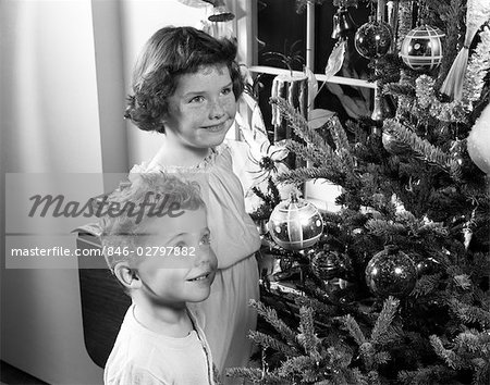 1950s BOY GIRL SMILING UP AT CHRISTMAS TREE DECORATIONS ORNAMENTS PINE FIR CANDLE IN WINDOW WISHING DREAMING