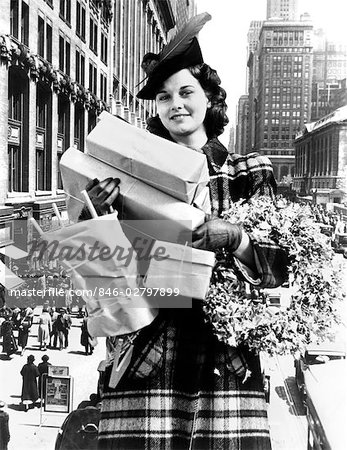 1930s 1940s WOMAN ARMS FULL CHRISTMAS SHOPPING PACKAGES & WREATH COMPOSITE WITH CITY STREET SCENE